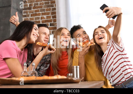 I giovani prendendo selfie a parte con una deliziosa pizza al chiuso Foto Stock