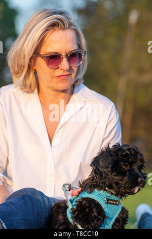 Una signora in una camicia bianca con la giovanissima cucciolo godendo un picnic Foto Stock