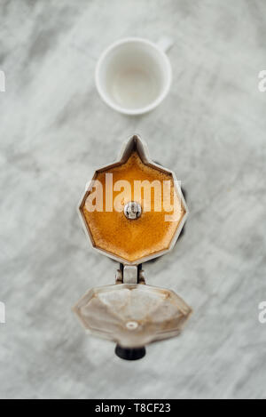 Moka pot con caffe' macinato di fresco e tazza bianca su sfondo grigio Foto Stock