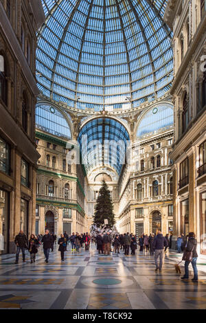 Lo spettacolare soffitto a cupola in vetro della Galleria Umberto I a Napoli, in Italia, con un grande albero di Natale e folle di acquirenti durante le festività. Foto Stock