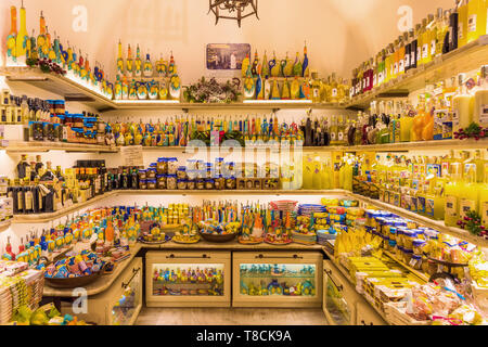 Bottiglie di liquore tradizionale al limoncello esposte in un colorato negozio di souvenir ad Amalfi, Italia. Regali italiani agli agrumi giallo brillante. Foto Stock