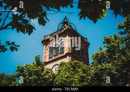 Torre dell'orologio dell'Università di Barcellona in Spagna attraverso il fogliame Foto Stock