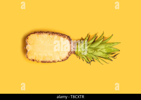 Concetto di estate. Mezzo fresco di ananas a fette su sfondo giallo. Vista dall'alto. Copia dello spazio. Piatto, laici vista superiore Foto Stock