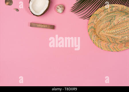 Noce di cocco, di foglie di palma, cappello, su uno sfondo rosa, vista dall'alto Foto Stock