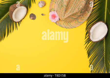 Hat, noci di cocco e foglie di palmo isolato su sfondo giallo, vista dall'alto Foto Stock