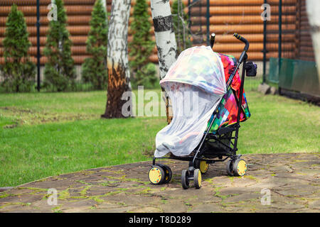 Bambino nel passeggino coperti con protezione di rete durante la fase di camminata. Bambino trasporto con anti-zanzara coperchio bianco. Midge protezione per i bambini durante la outdoor Foto Stock