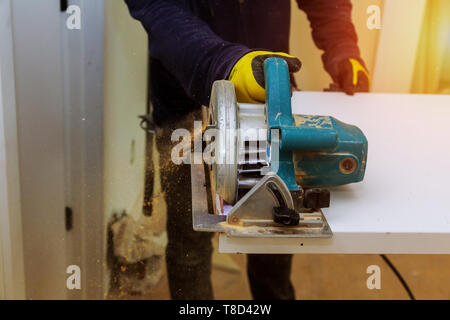 Contraente utilizzando una sega elettrica per tagliare pannelli porta alla costruzione di una nuova casa Foto Stock