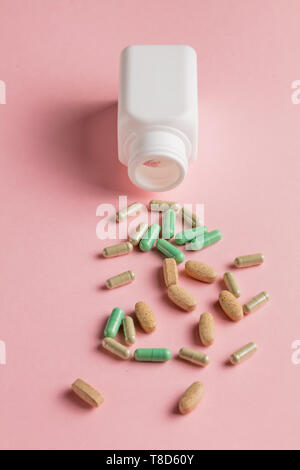 Molte pillole sparsi sul tavolo rosa. top view photo. Stile minimal. Foto Stock
