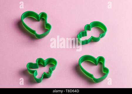 Verde di natale cookie cutters sulla rosa table.anno nuovo. vacanze, utile strumento per chef. top view foto Foto Stock