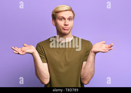 Clueless e perplesso giovane uomo bello avente espressione confusa, scrollare le spalle come se dicendo: non so Foto Stock