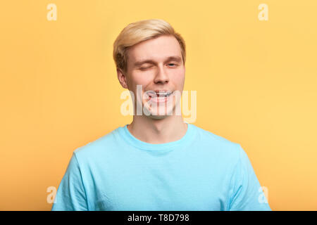 Uomo pazzo in un elegante blu T-shirt rendendo volti mentre guardando la telecamera, close up ritratto, MIMIC, grimace concetti Foto Stock