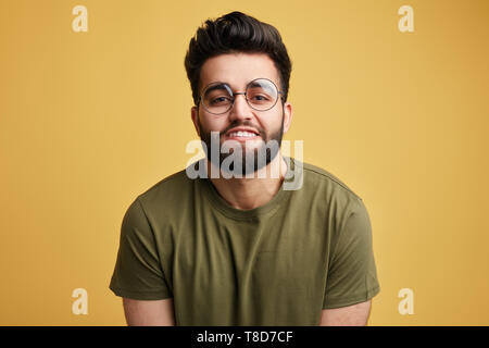 Attraente awesome positivo uomo innocuo in bicchieri showi ng i suoi denti bianchi. close up photo isolati a sfondo giallo. obbediente guy.Concetto di obbedienza Foto Stock