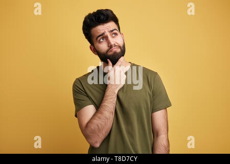 Soluzione del problema. giovane uomo carino dispone di un problema, uono. guarda in alto, costituisce un'idea isolati a sfondo giallo Foto Stock