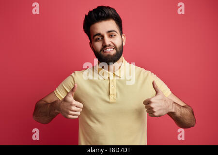 Giovane ragazzo positiva rendendo un pollice in alto gesto isolato su sfondo rosa. close up verticale Foto Stock