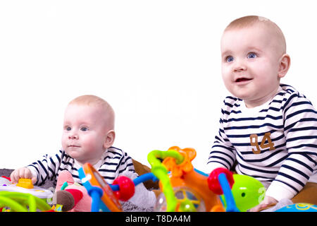 Adorabili e non-gemelli, noto anche come gemelli fraterni o dizygotic gemelli giocare con giocattoli isolati su sfondo bianco. Due ragazzi felici, uno sittin Foto Stock