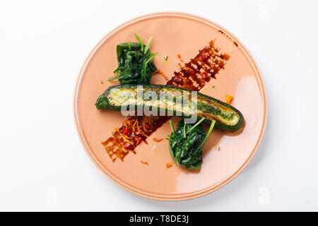 Zucchine alla griglia / Courgette con salsa di melograno e spinaci saltati isolati su bianco. Foto Stock