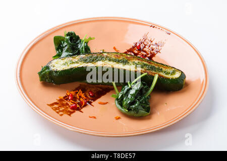 Zucchine alla griglia / Courgette con salsa di melograno e spinaci saltati isolati su bianco. Foto Stock