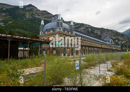 Lato posteriore della abbandonato a Canfranc stazione ferroviaria internazionale con Borreguil de la Cuca picco in background (Pirenei, Huesca, Aragona, Spagna) Foto Stock
