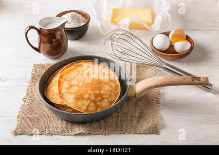 Padella con gustose frittelle sottili e gli ingredienti sul tavolo Foto Stock