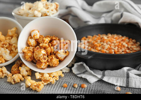 Bocce con deliziosi popcorn e kernel su sfondo di legno Foto Stock