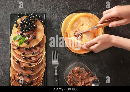 Macchiatura di donna pasta cioccolato sulle frittelle sottili Foto Stock