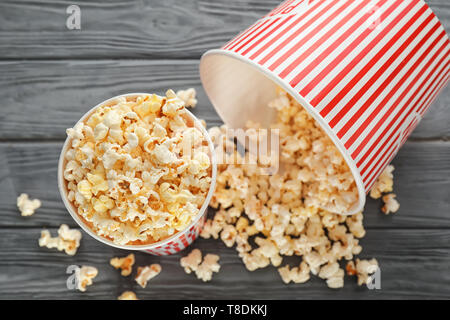 Tazze con deliziosi popcorn su sfondo di legno Foto Stock