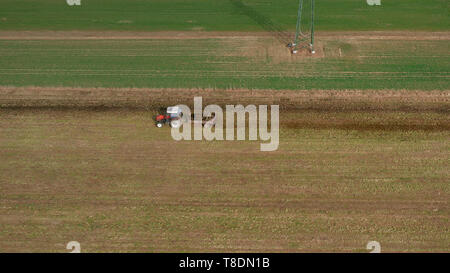 Vista aerea di un trattore rosso e il rimorchio trasporta un carico di letame sulla strada, agricoltura, fertiliying e il trattamento del terreno Foto Stock