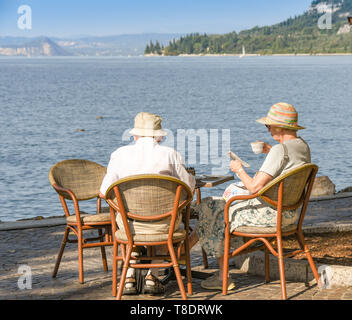 Il LAGO DI GARDA, Italia - Settembre 2018: uomo maturo e donna seduta a un tavolo in riva al lago di Garda sul Lago di Garda relax e avente una tazza di tè
