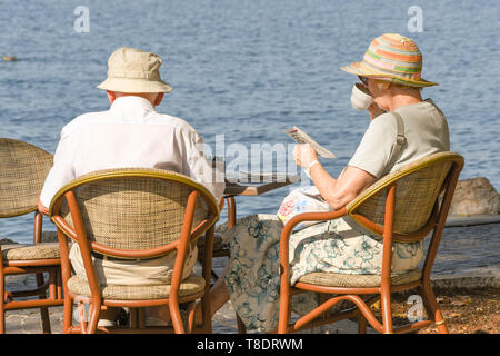 Il LAGO DI GARDA, Italia - Settembre 2018: uomo maturo e donna seduta a un tavolo in riva al lago di Garda sul Lago di Garda relax e avente una tazza di tè Foto Stock