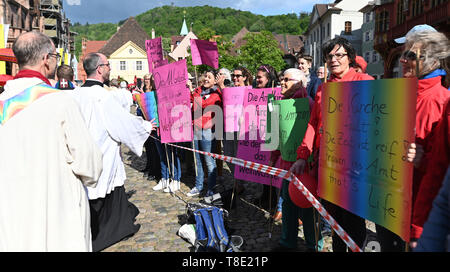 Freiburg, Germania. Il 12 maggio 2019. I sacerdoti di fronte alla cattedrale e passare le donne di Maria 2.0 iniziativa delle donne cattoliche della comunità di nell Arcidiocesi di Friburgo. Le donne detengono diversi banner nell'aria. Circa 400 donne hanno invitato la Chiesa a ripensare e a promuovere la giustizia di genere in una azione di protesta. Credito: Patrick Seeger/dpa/Alamy Live News Foto Stock