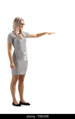 A piena lunghezza shot di una giovane donna gesticolando con la mano e che mostra l'altezza di qualcosa di isolato su sfondo bianco Foto Stock