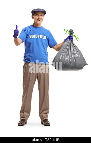 A piena lunghezza Ritratto di un uomo anziano volontario tenendo un sacco dei rifiuti e mostrando pollice in alto isolato su sfondo bianco Foto Stock