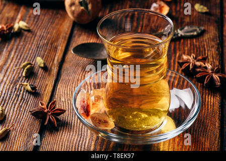 Il tè speziato con anice stellato, cardamomo e essiccato in calce armudu vetro sopra una superficie di legno Foto Stock