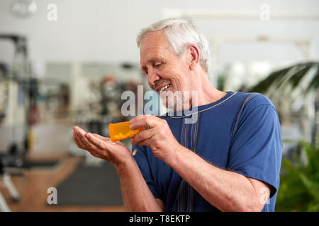 Uomo di colare una pillola da in mano. Uomo anziano prendendo quotidianamente la medicina a consumare. Sport Nutrition concetto. Foto Stock