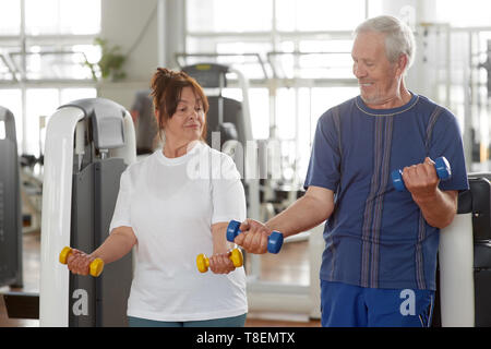 Senior caucasica persone per gli esercizi in palestra. Coppia di anziani il sollevamento pesi insieme al centro fitness. Persone, sport, stile di vita sano. Foto Stock