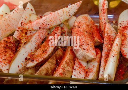 Preparazione per la cottura di Spicchi di patate con peperoncino e paprica, cibo colorato Foto Stock