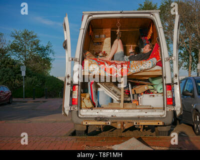 Alternative di vivere in città - un uomo si siede nel suo convertito home van nel centro della Baia di Cardiff Foto Stock