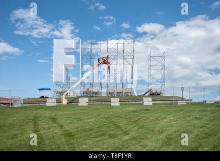 Lavoratori edili installazione di segno di grandi dimensioni in un campo vuoto. Foto Stock