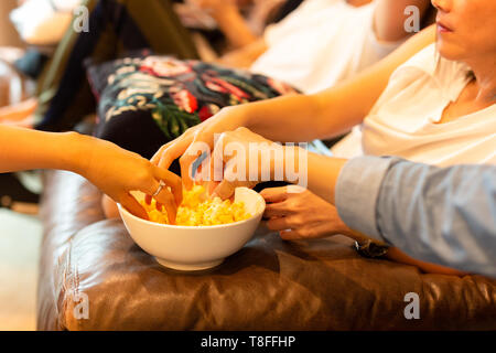 Donna mani tenendo il popcorn da coppa guardando film con un amico. Foto Stock