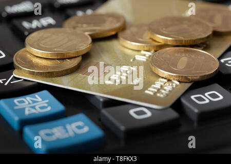 La carta di credito e le monete sono sulla calcolatrice. Affari e finanza. Foto Stock