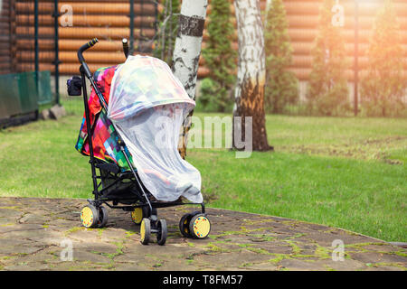Bambino nel passeggino coperti con protezione di rete durante la fase di camminata. Bambino trasporto con anti-zanzara coperchio bianco. Midge protezione per i bambini durante la outdoor Foto Stock