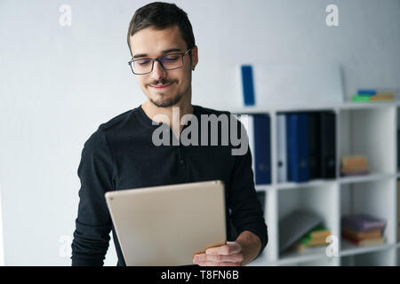 Giovane uomo che lavora con la compressa, ricezione di chiamata video, parlando con i partner Foto Stock