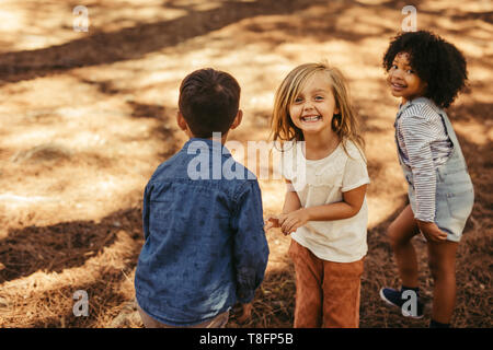 Bellissima ragazza con gli amici in un parco. Un gruppo di bambini che giocano nella foresta. Foto Stock