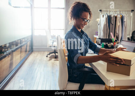 La donna il confezionamento della scatola di cartone sulla sua scrivania. Imprenditrice la preparazione di prodotto per fornire al cliente. Foto Stock