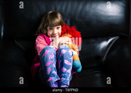 Carina ragazza con il suo giocattolo sul divano di casa Foto Stock