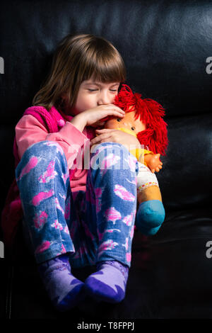 Carina ragazza con il suo giocattolo sul divano di casa Foto Stock