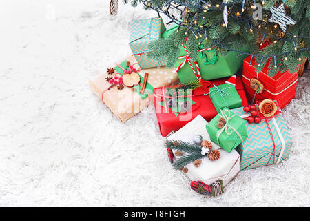 Molti regali di Natale sul pavimento sotto abete Foto Stock