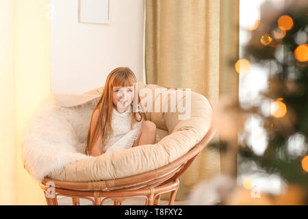 Carino bambina rilassarsi nella lounge chair alla vigilia di Natale Foto Stock