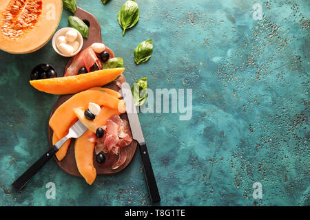 Deliziosa fette di melone con prosciutto e formaggio mozzarella sul colore di sfondo Foto Stock