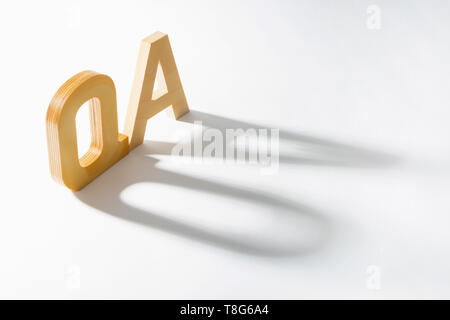 Alfabeto di legno Q un ombra e riflessione. Domande e risposte. Foto Stock